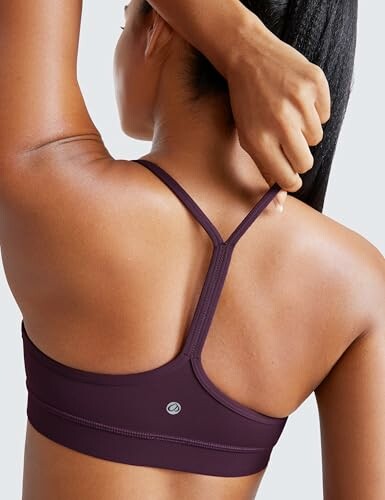 Mujer ajustando un sujetador deportivo morado.