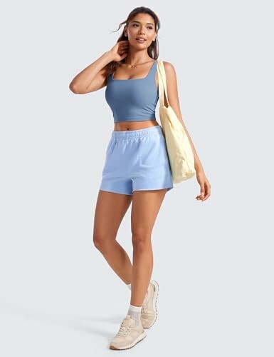 Mujer con ropa casual y bolso, fondo gris.